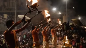 Homens segurando taças com fogo realizam cerimônia hindu em ghat de Varanasi 