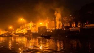 Fumaça sobe sobre o rio Granges e as casas em Cerimônia de cremação de copos em Ghat de Varanasi, durante a noite. A cidade velha é o melhor lugar onde ficar em Varanasi