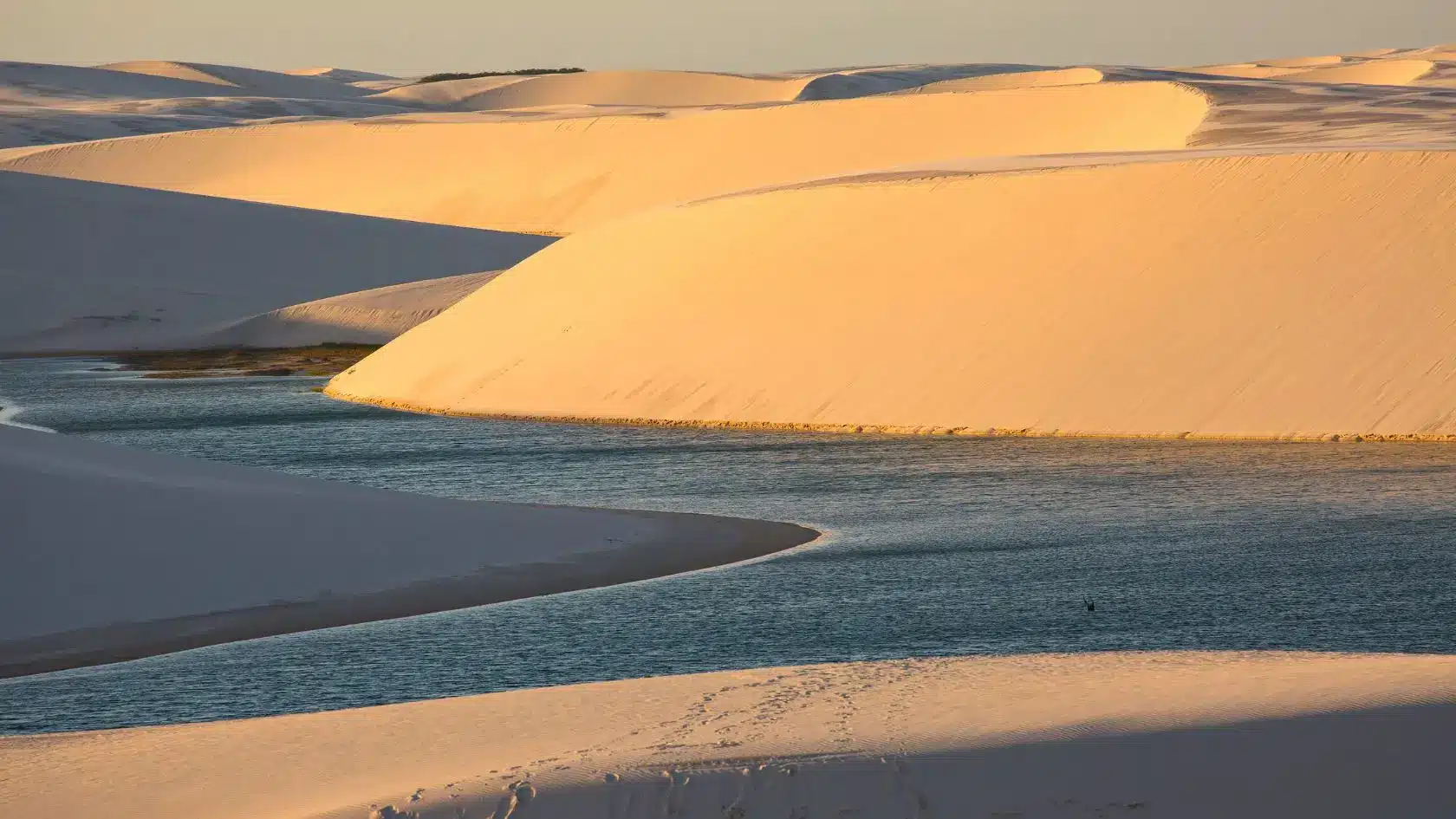 Vista dos lençóis maranhenses ao por do sol, com piscinas naturais no centro. Veja os melhores locais onde ficar em Barreirinhas para explorar o parque!