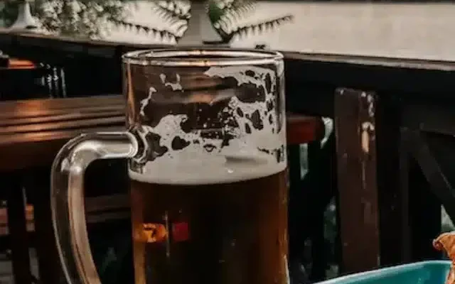 Imagem de uma cerveja com um hekk (merluza frita) em uma mesa de restaurante à beira rio na Romai Part, praia do Danúbio, em Budapeste