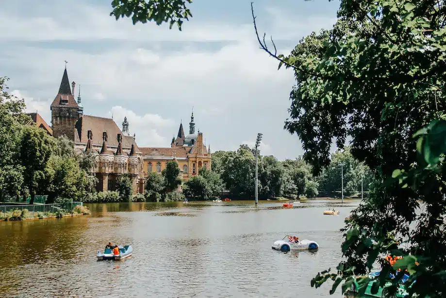Foto de um lago com pedalinhos e um castelo no fundo no Parque da Cidade, Budapeste