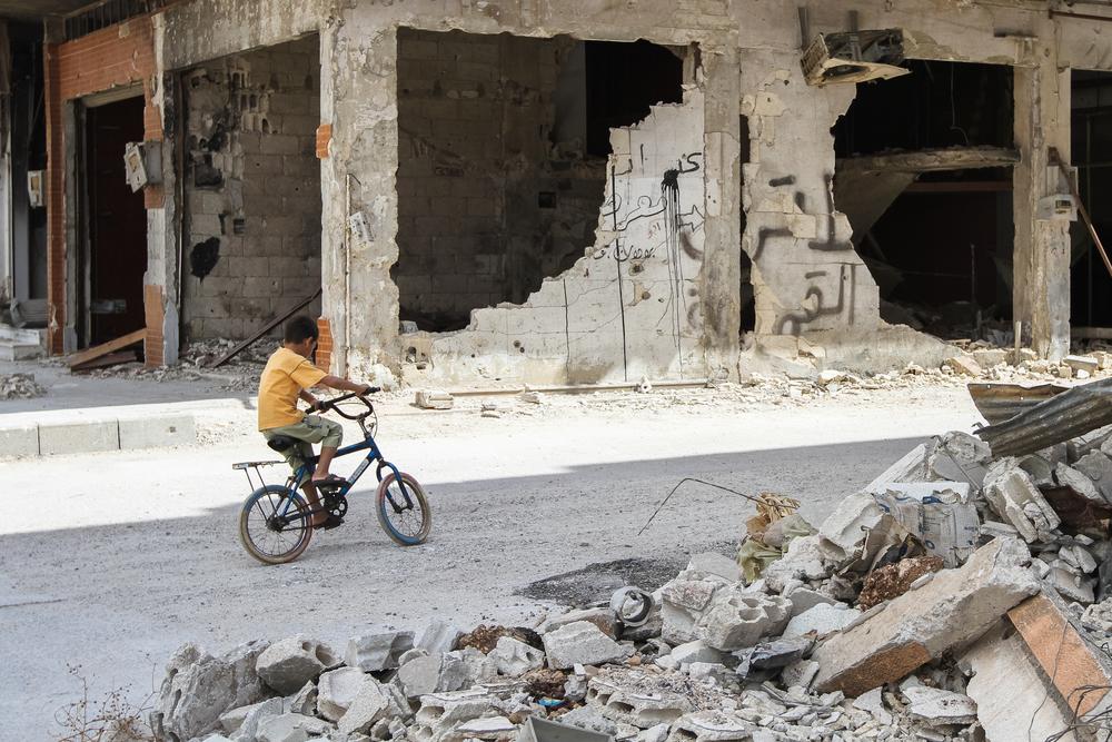 Menino passeia de bicicleta em Homs, na Síria. Crise humanitária no país se arrasta por anos.