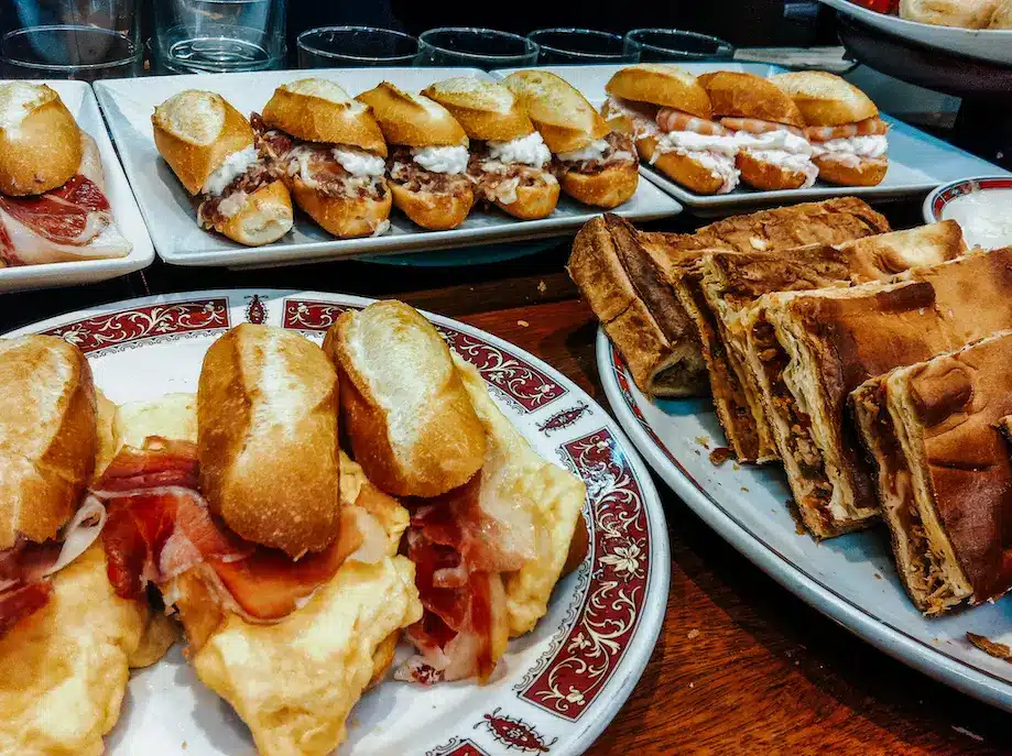 Pinxtos (saduiches pequenos e fatias de torta) expostos em um balcão em uma taverna em San Sebastián