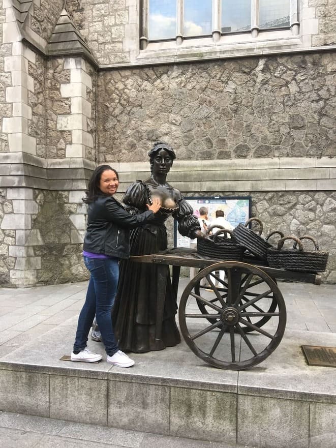 Mulher pousando para foto ao lado de uma estátua