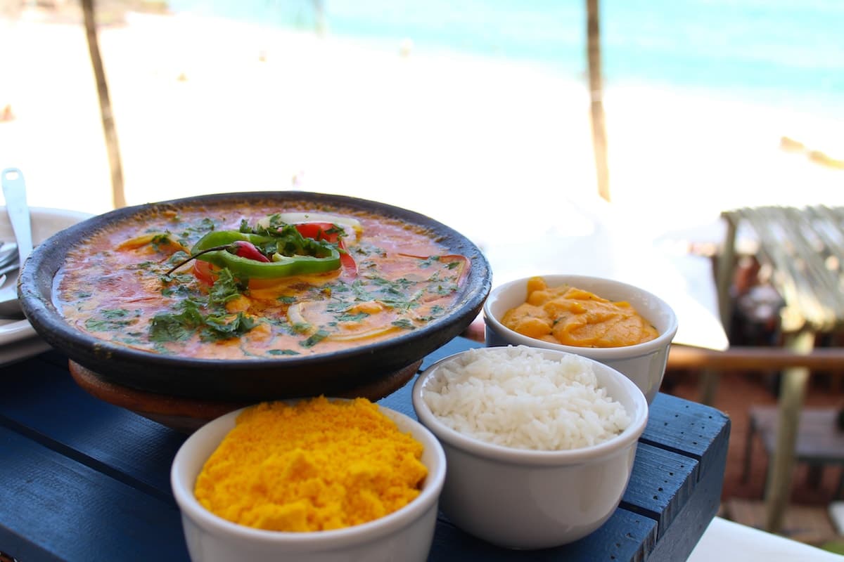 Comidas típicas do Cerá: moqueca servida em uma mesa na praia com arroz e farofa