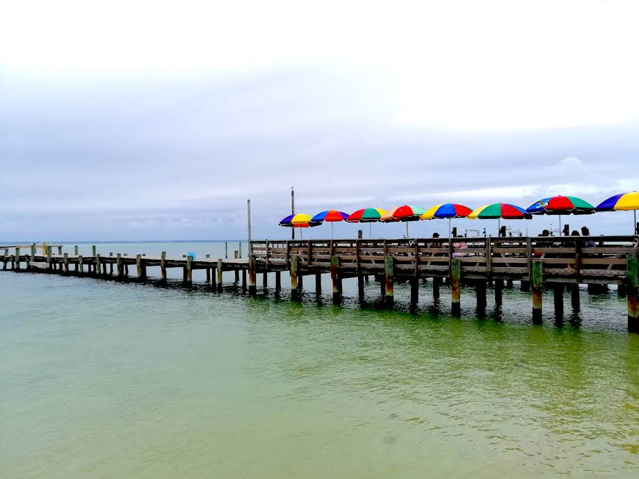 Cadeiras com sombrinhas coloridas sobre pier em Restaurante Deweys, em Destin 