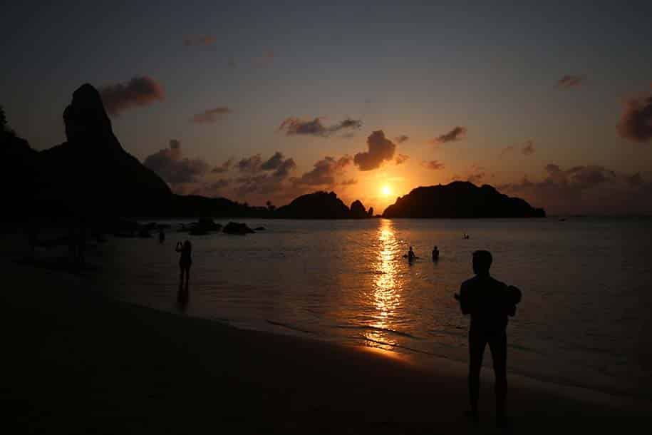 Pôr do sol na Praia do Cachorro, homem carrega bebê, em Fernando de Noronha