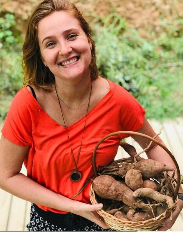 juliana carregando uma cesta de mandioca, alimento orgânico