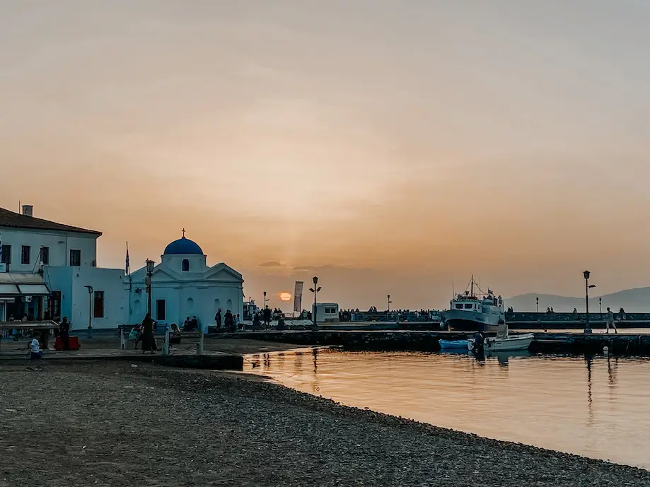 Por do sol em praia no centro de Mikonos, com uma igreja ortodoxa no fundo