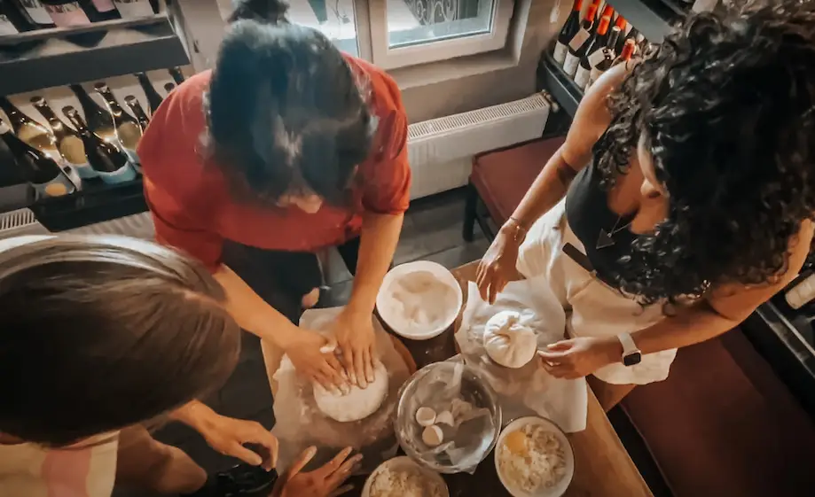 Foto de uma aula de gastronomia georgiana em Tbilisi. Quatro pessoas preparam a massa de um khinkali.