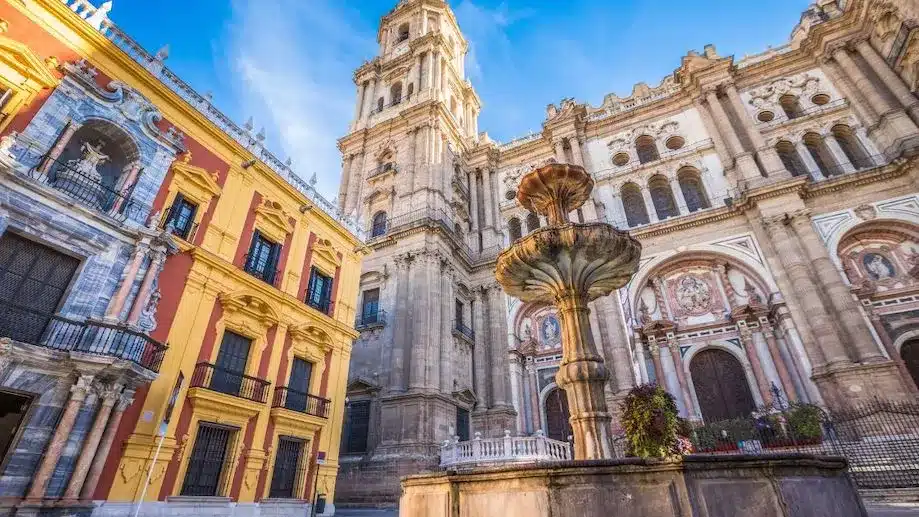 Igreja do centro histórico de Málaga com um chafariz na frente. 