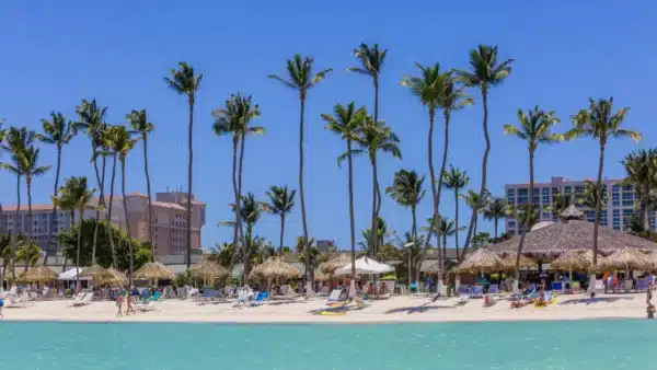 Vista de praia de Palm Beach, Aruba, com os hotéis ao fundo e espreguiçadeiras nas areias