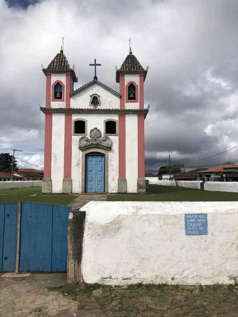 Melhores pousadas de Lavras Novas. Foto mostra igreja principal da cidade, com duas torres e detalhes avermelhados. 